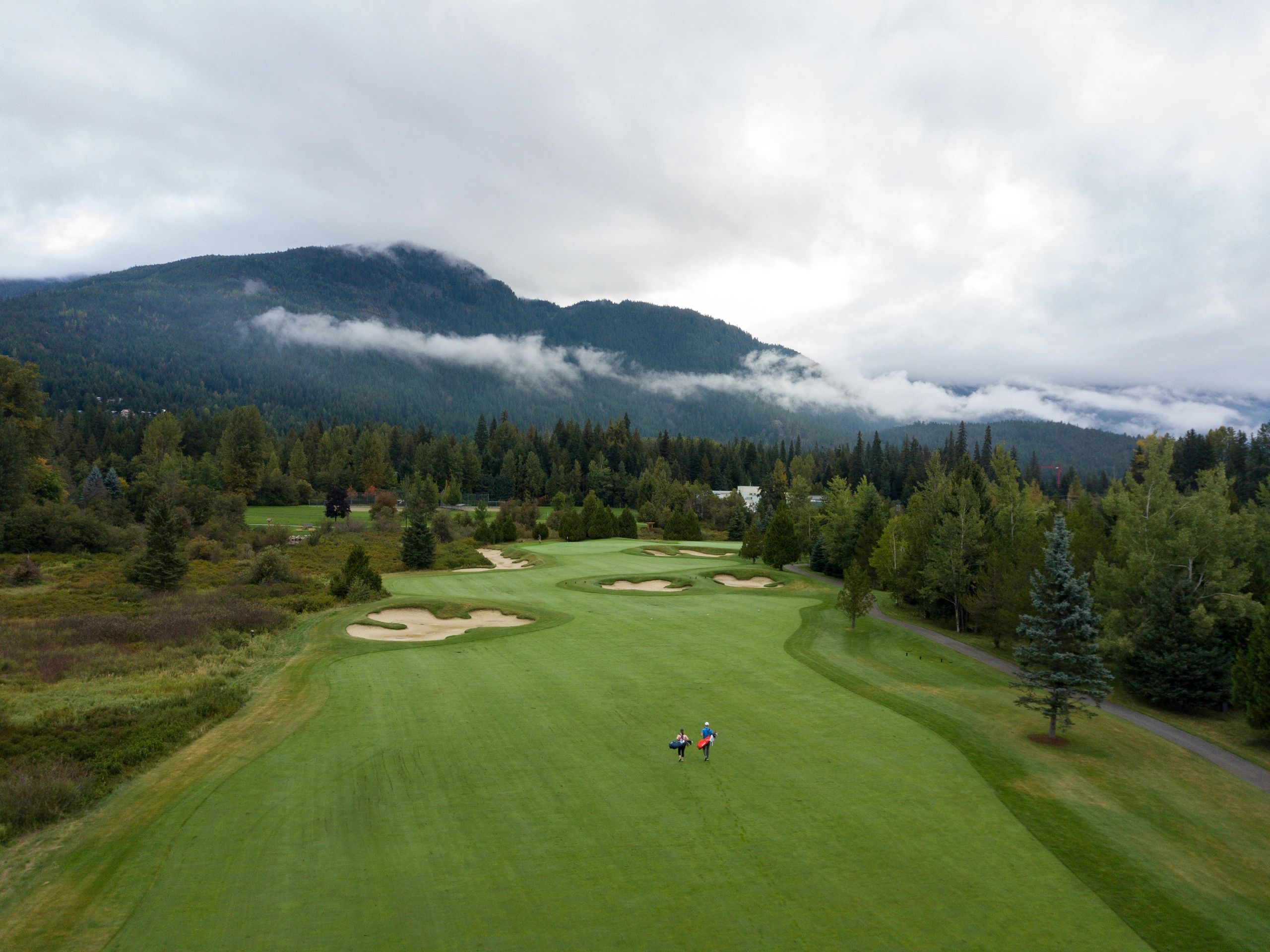 Golfers walking the fairway between practice and play