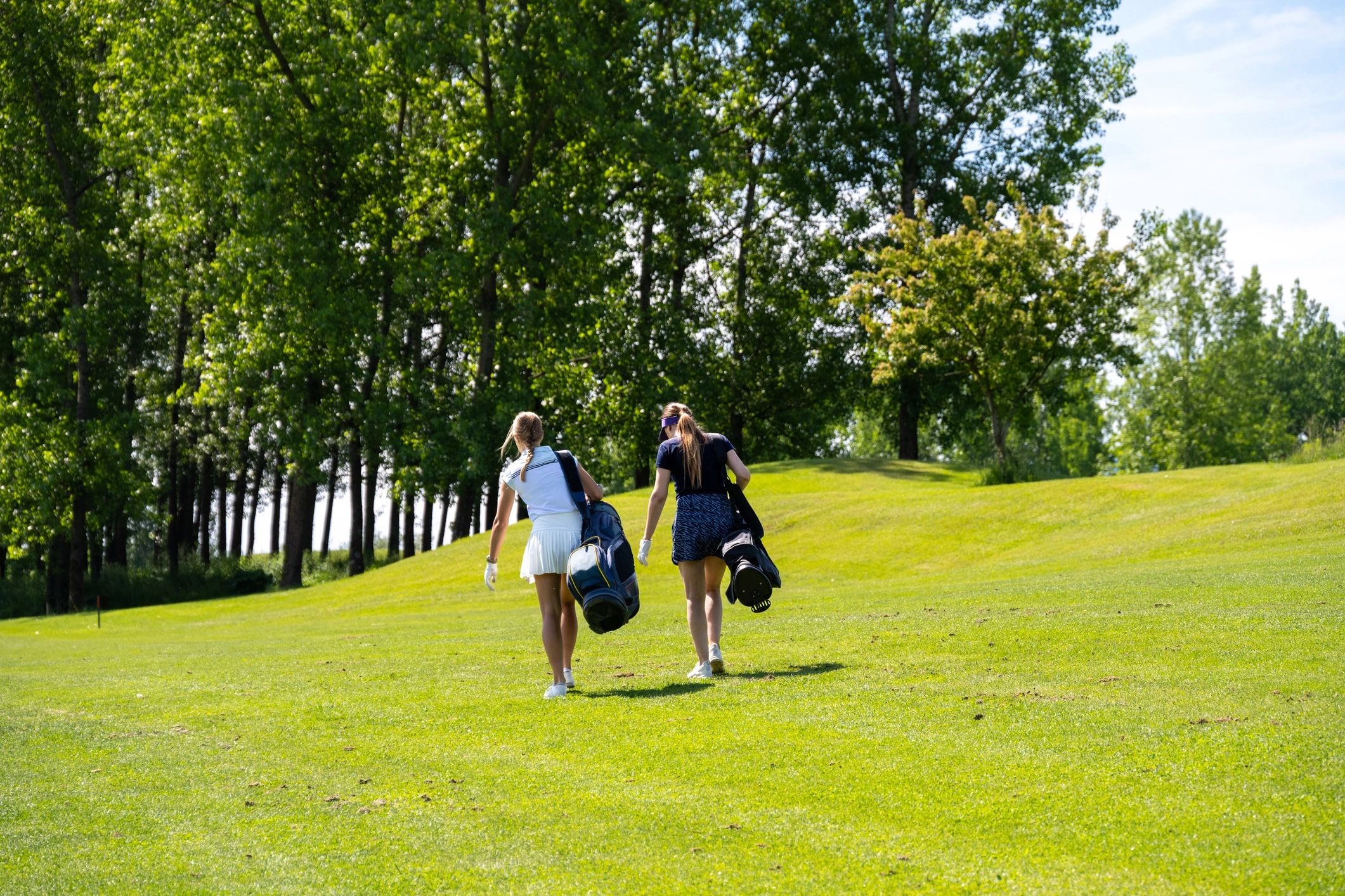 Golfers carrying bags on a fairway